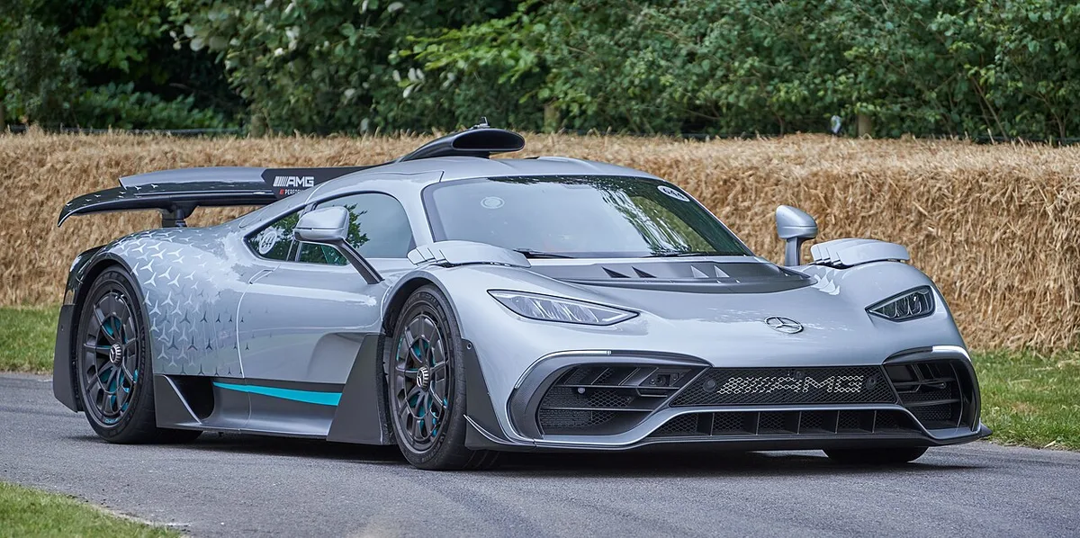 A silver production Mercedes-AMG ONE with teal stripes driving at the 2022 Goodwood Festival of Speed