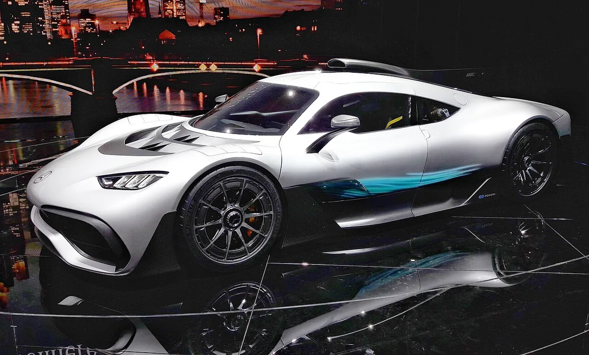 A silver Mercedes-AMG Project ONE concept with teal accents on display at night during the 2017 Frankfurt motor show