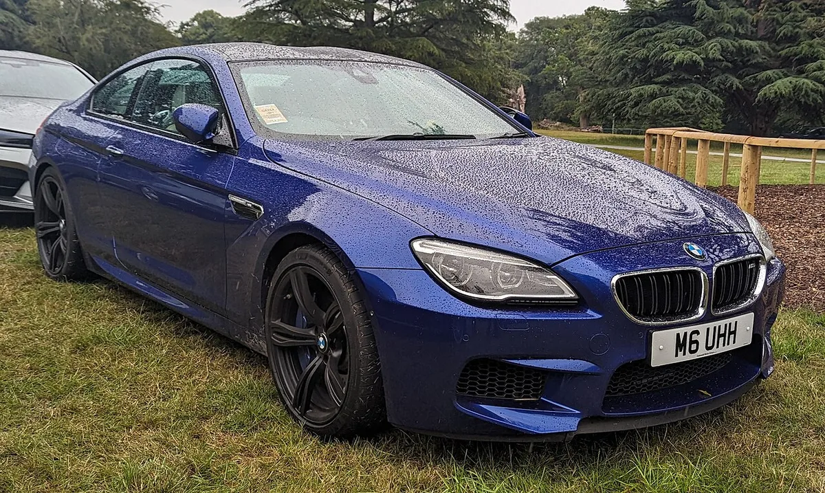 A blue BMW M6 coupe from the twin-turbo V8 generation, seen from the front three-quarter