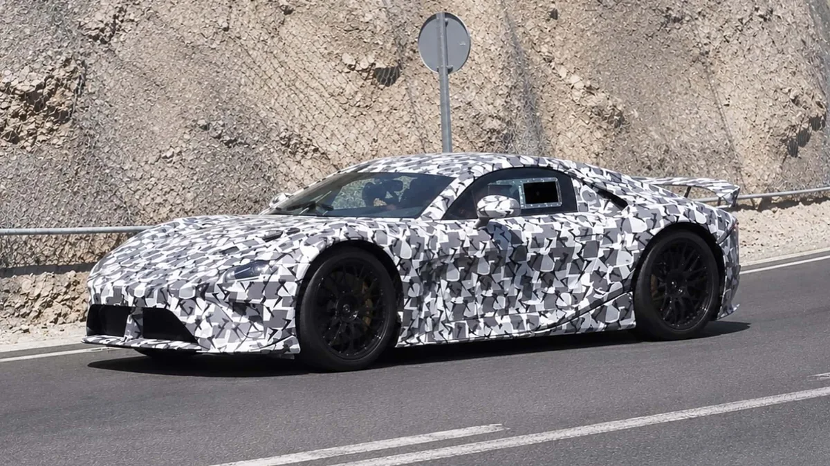 A camouflaged prototype of the new electric Lexus LFA on a road from the front three-quarter view, with its rear wing raised