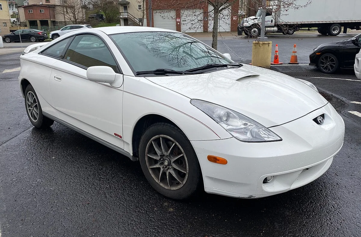 A white 2002 Toyota Celica GT-S parked on wet pavement, seen from the front right