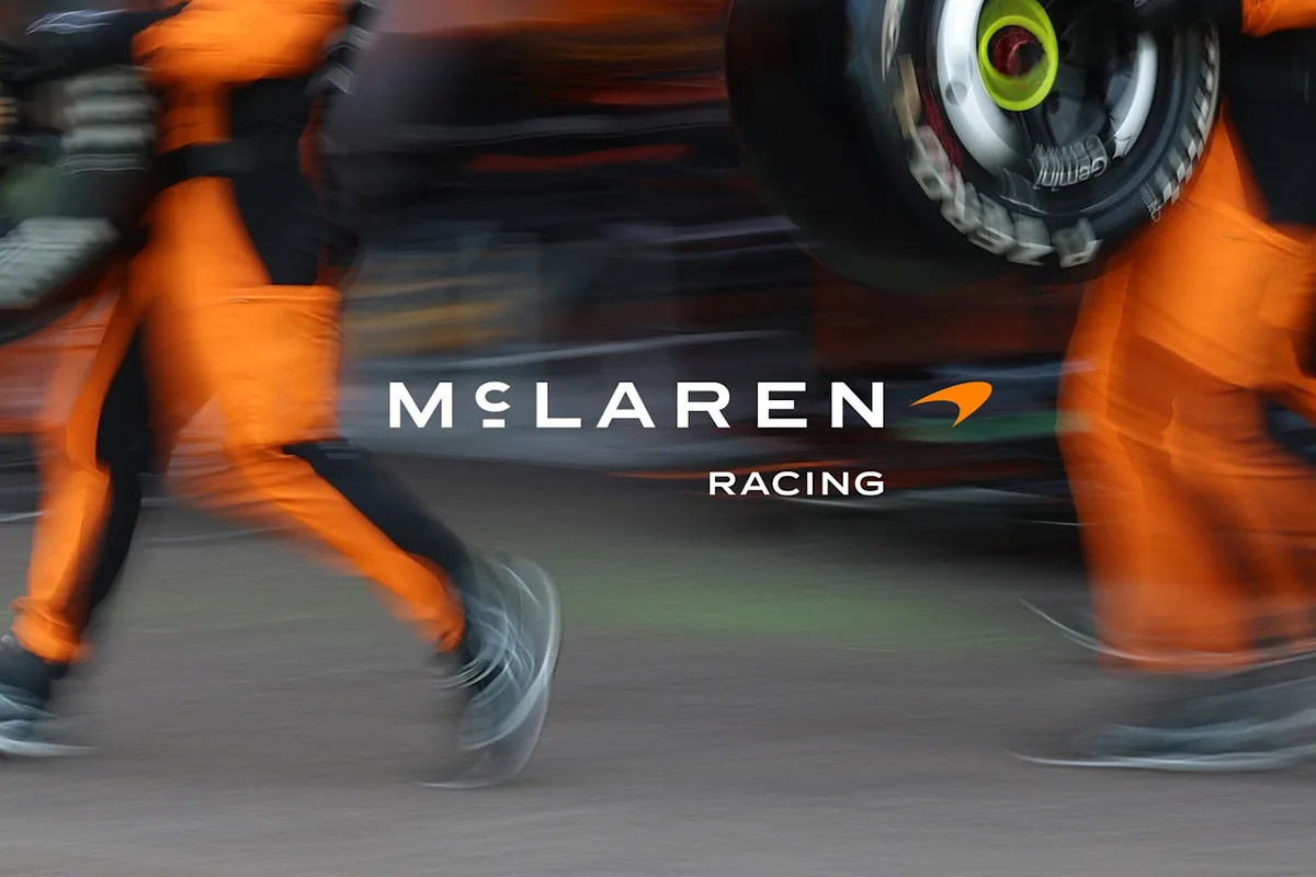 The new McLaren Racing wordmark over a blurred photo of McLaren pit crew members