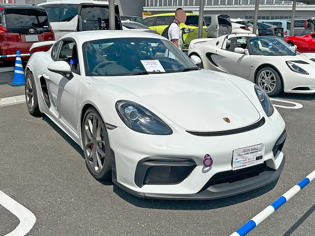 A white Porsche 718 Cayman GT4 RS seen from the front three-quarter angle at a car show