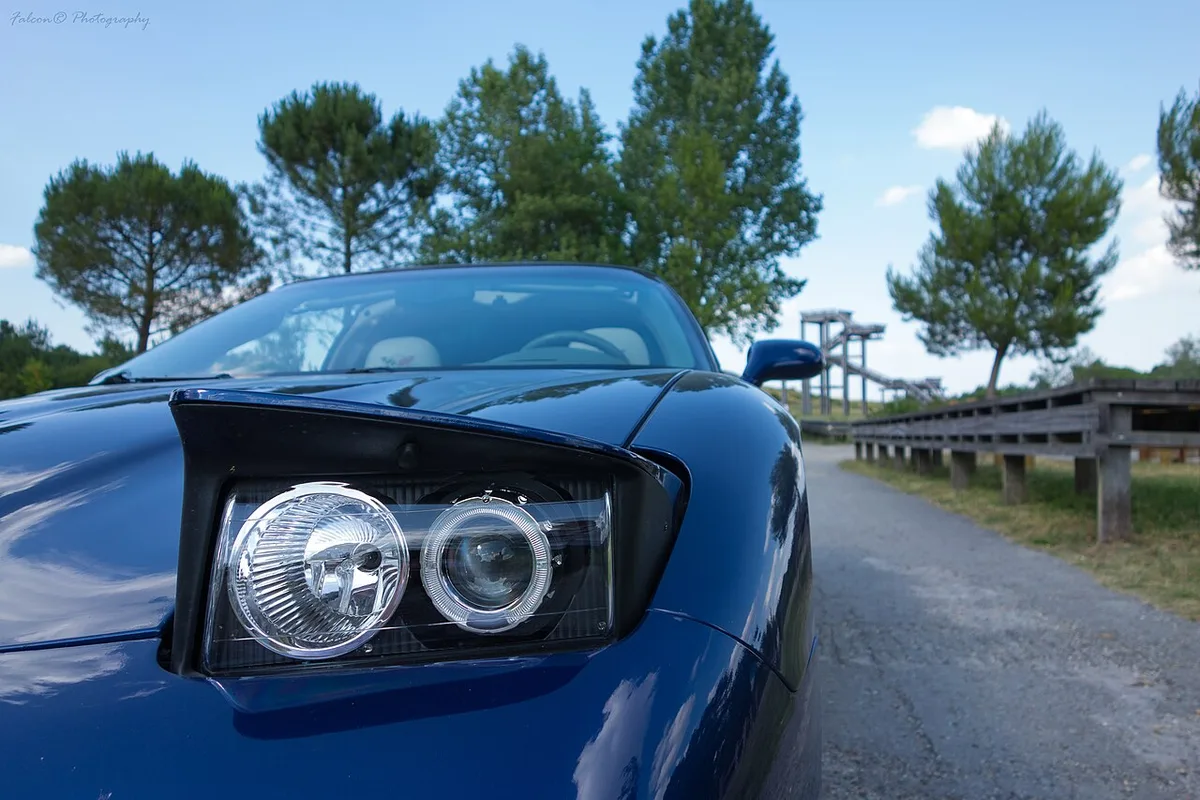 The raised pop-up headlight pod on a blue 2004 Chevrolet Corvette C5, with its two round lenses showing