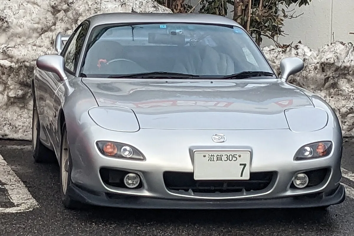 Front view of a silver Mazda RX-7 FD3S with its low nose and slim headlights, parked outdoors