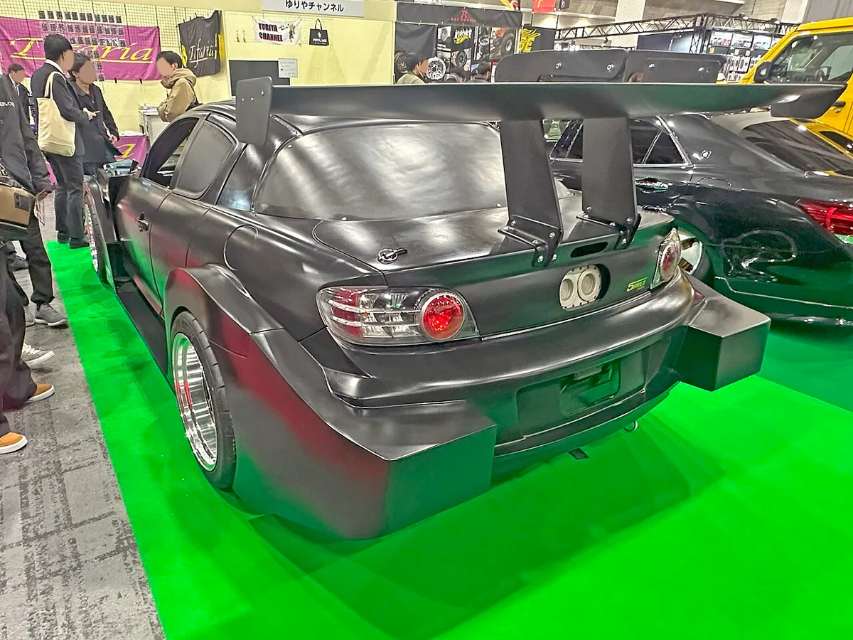 Rear view of a black Mazda RX-8 built to a Tsukuba time attack spec, with a tall rear wing and a large diffuser, at Osaka Auto Messe 2025